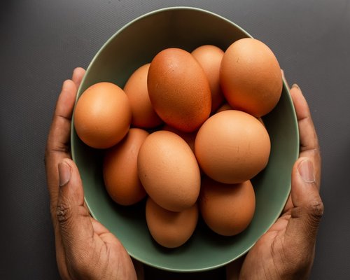 Organic chicken eggs in a modern plate accompanied by fresh kitchen ingredients