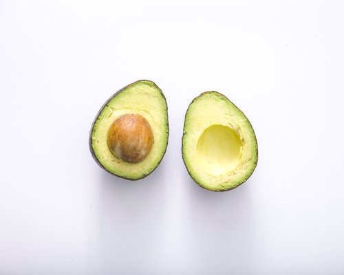 A close-up of a perfectly ripe avocado sliced in half with the pit visible